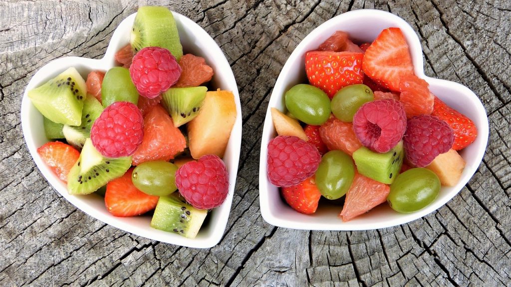 deux salades de fruits dans ramequins en forme de coeur avec morceaux de fraise kiwi framboises raisins